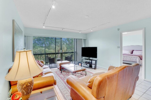 living room with a textured ceiling, light tile patterned floors, and track lighting