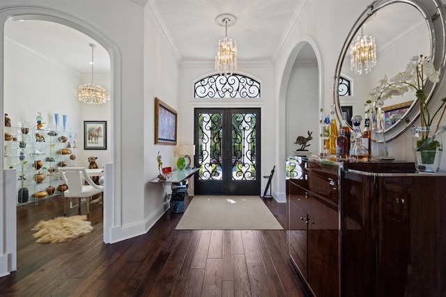 entryway with an inviting chandelier, dark hardwood / wood-style flooring, crown molding, and french doors