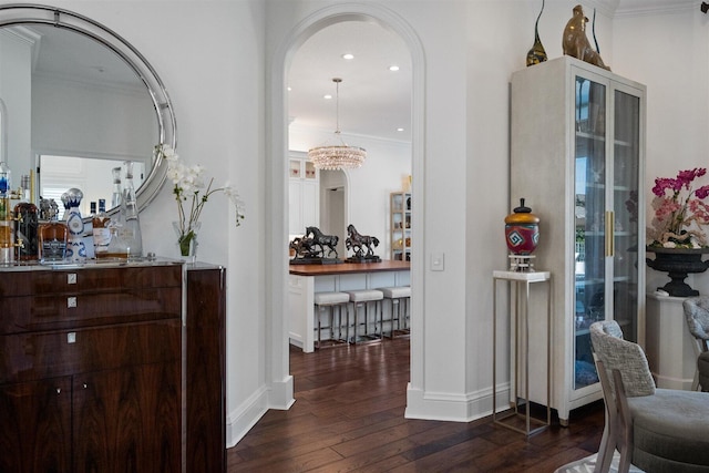 hallway featuring dark hardwood / wood-style flooring, ornamental molding, and a notable chandelier