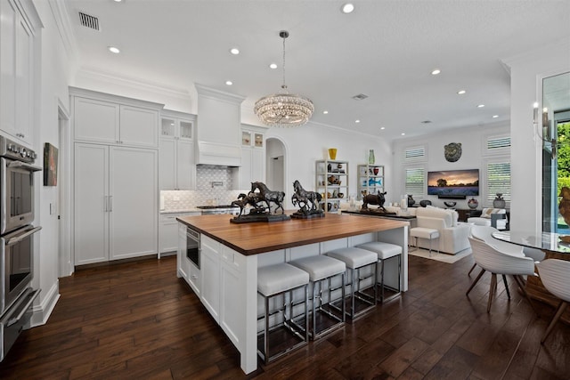 kitchen with white cabinets, wood counters, a center island, and decorative backsplash