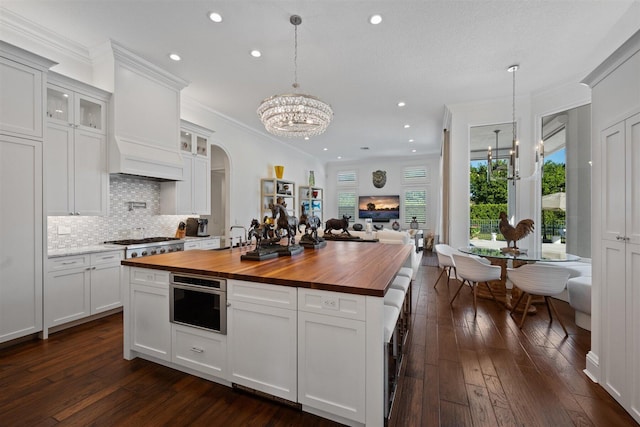 kitchen with wood counters, decorative light fixtures, and white cabinets