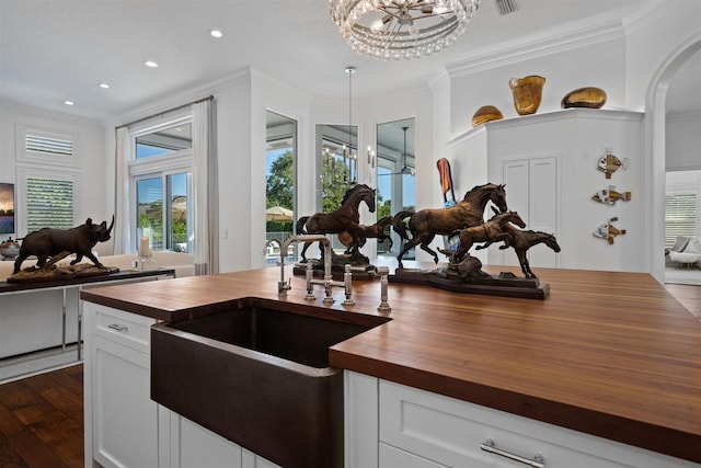 kitchen with butcher block counters, crown molding, a chandelier, decorative light fixtures, and white cabinets