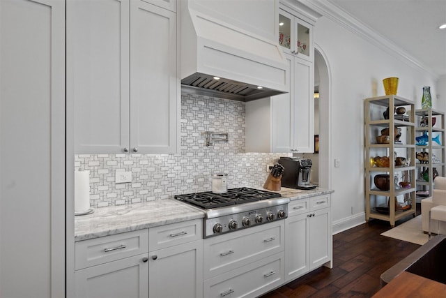 kitchen featuring decorative backsplash, white cabinets, custom range hood, and stainless steel gas stovetop