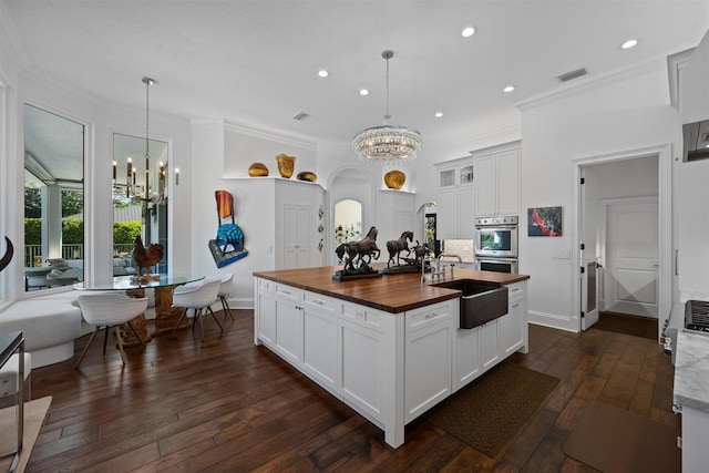 kitchen with white cabinets, decorative light fixtures, a notable chandelier, and sink