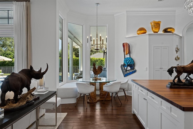 dining space featuring dark hardwood / wood-style floors, an inviting chandelier, and crown molding