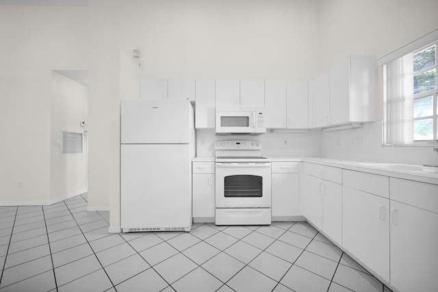 kitchen with light tile patterned floors, white appliances, white cabinetry, and sink