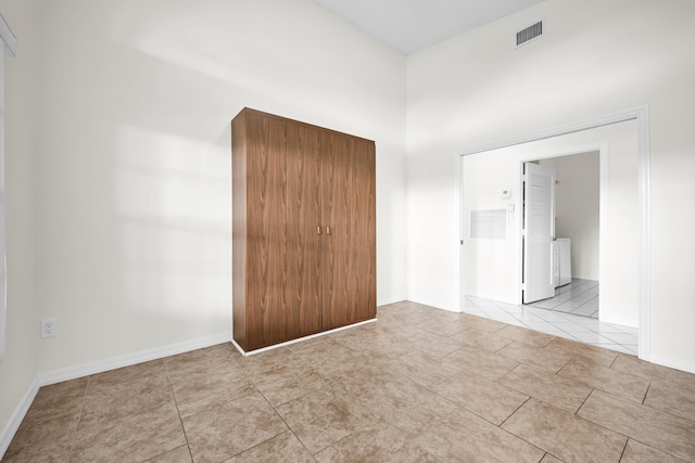 unfurnished bedroom featuring connected bathroom, washer / clothes dryer, and a towering ceiling