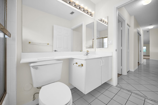 bathroom featuring tile patterned floors, vanity, a textured ceiling, a shower with door, and toilet