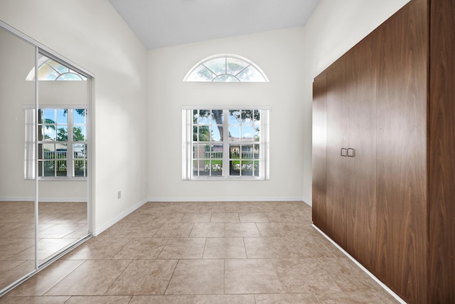 tiled spare room featuring high vaulted ceiling and a healthy amount of sunlight