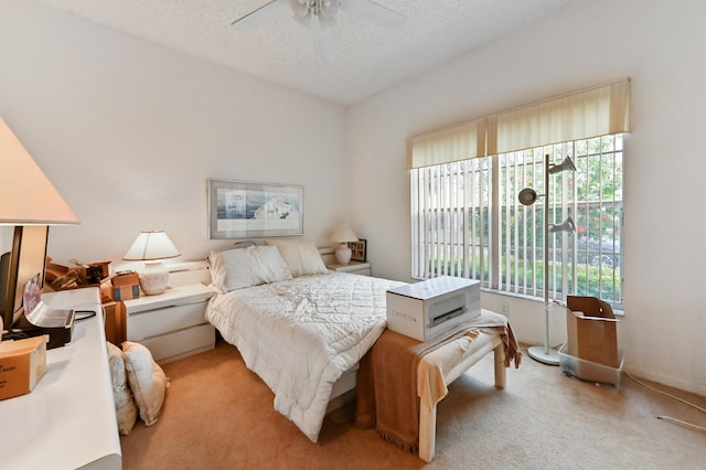 bedroom featuring ceiling fan, light colored carpet, and a textured ceiling