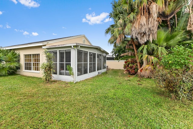 back of property with a lawn and a sunroom