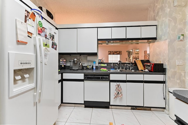 kitchen with a textured ceiling, white cabinetry, white fridge with ice dispenser, and sink