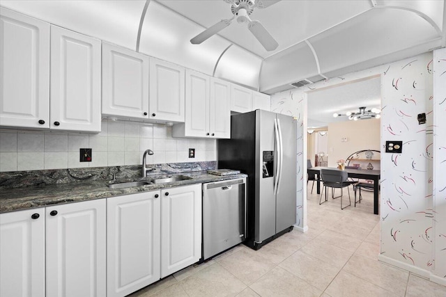 kitchen with appliances with stainless steel finishes, dark stone counters, ceiling fan, sink, and white cabinets