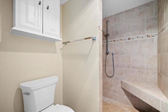 bathroom featuring a tile shower and toilet