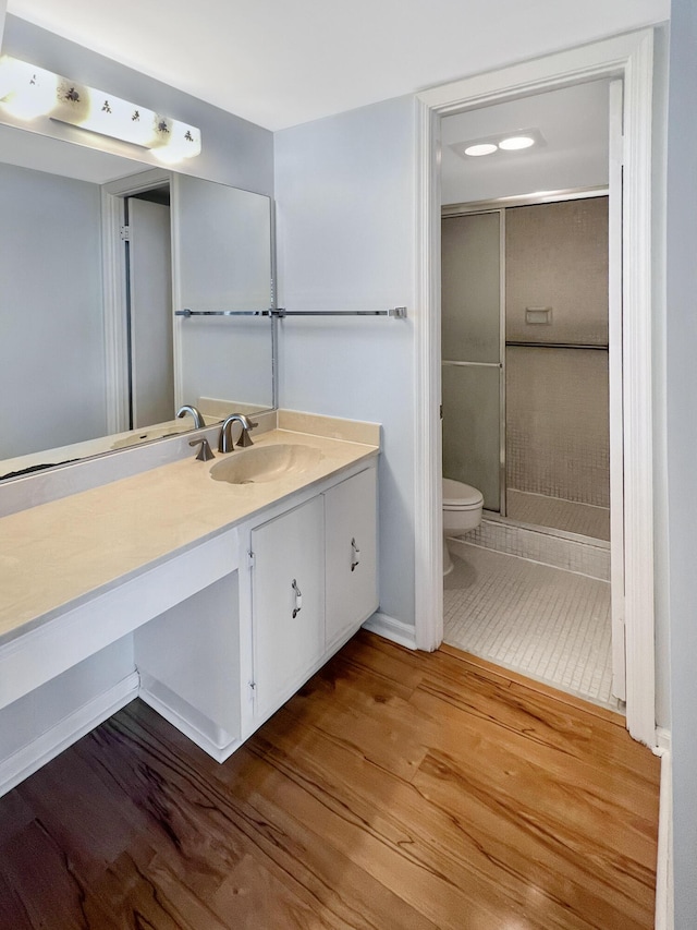 bathroom featuring vanity, hardwood / wood-style flooring, toilet, and a shower with door