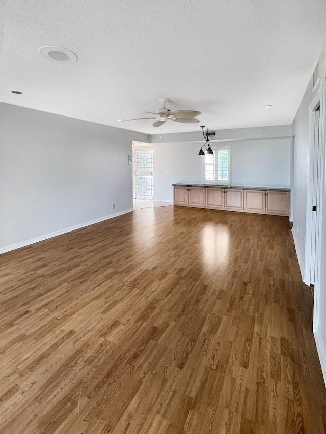 unfurnished living room with a textured ceiling, dark hardwood / wood-style floors, and ceiling fan