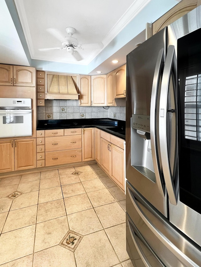 kitchen with stainless steel refrigerator with ice dispenser, white oven, light brown cabinets, and custom exhaust hood