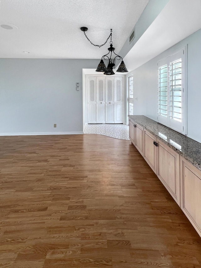 interior space featuring a textured ceiling, dark wood-type flooring, and an inviting chandelier