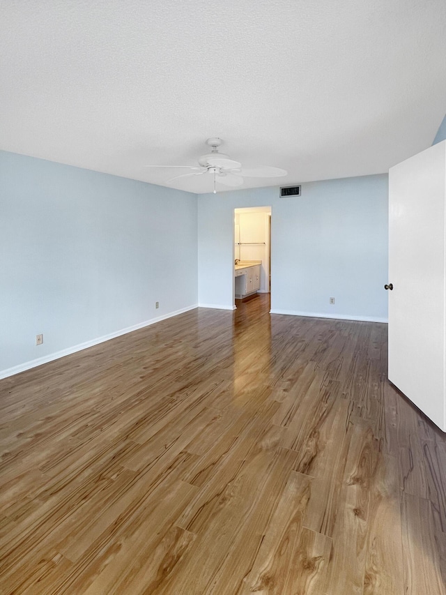 unfurnished room featuring ceiling fan, wood-type flooring, and a textured ceiling