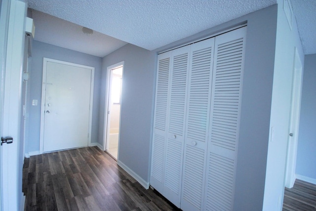 hall with a textured ceiling and dark hardwood / wood-style floors