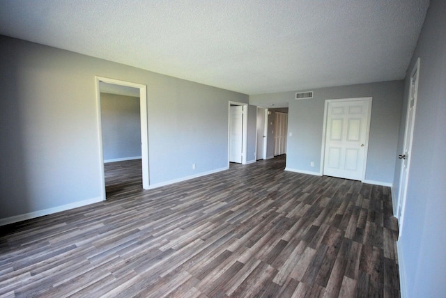 spare room featuring dark hardwood / wood-style floors and a textured ceiling