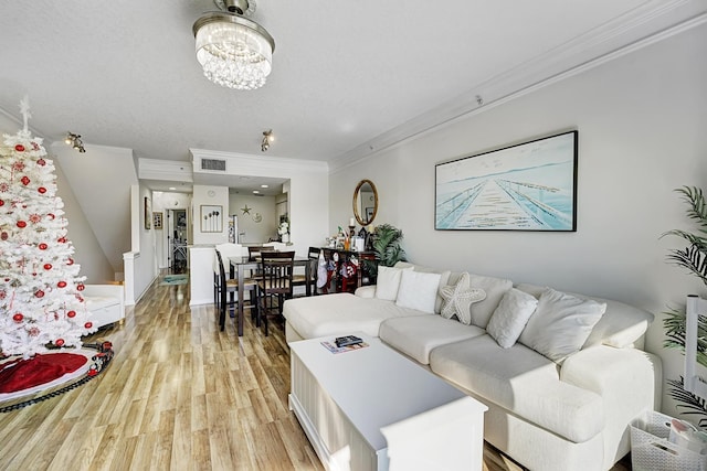 living room featuring ornamental molding, a notable chandelier, and light wood-type flooring