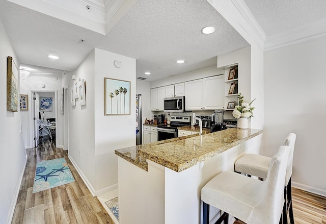 kitchen with white cabinetry, stone counters, stainless steel appliances, kitchen peninsula, and a textured ceiling