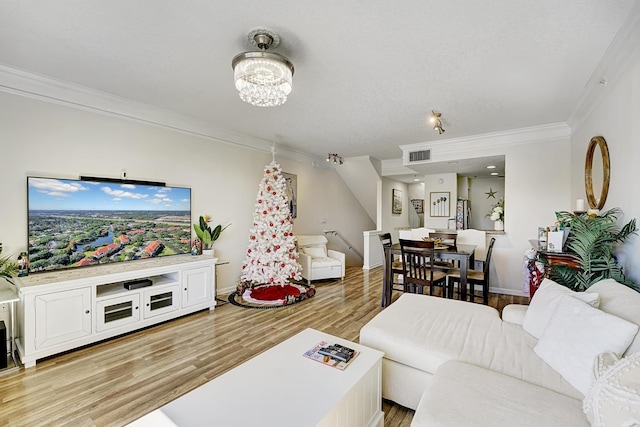 living room featuring an inviting chandelier, ornamental molding, and light wood-type flooring