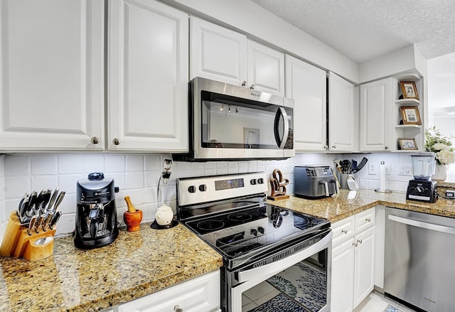 kitchen with stainless steel appliances, tasteful backsplash, light stone countertops, and white cabinets