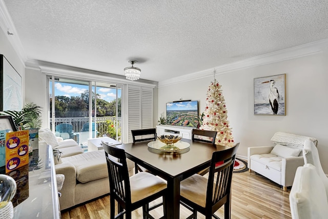 dining room with crown molding, light hardwood / wood-style floors, and a textured ceiling