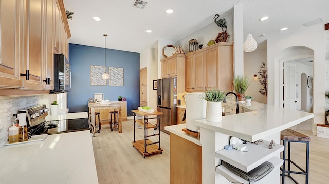 kitchen featuring stainless steel appliances, a kitchen breakfast bar, light hardwood / wood-style floors, pendant lighting, and decorative backsplash