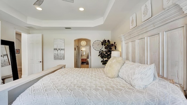 bedroom with a raised ceiling, ceiling fan, and wood-type flooring