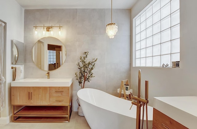 bathroom featuring tile patterned flooring, vanity, a bath, and tile walls