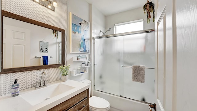 full bathroom featuring backsplash, vanity, toilet, and bath / shower combo with glass door