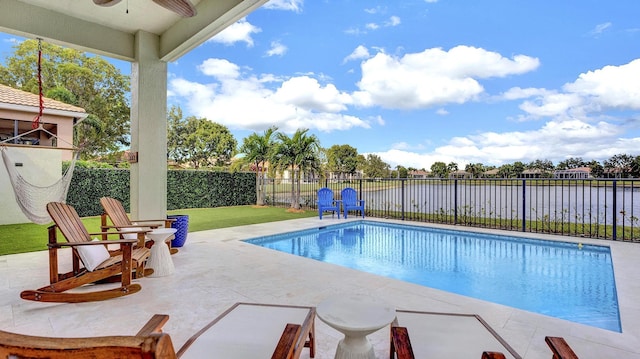 view of swimming pool with a lawn, ceiling fan, a water view, and a patio