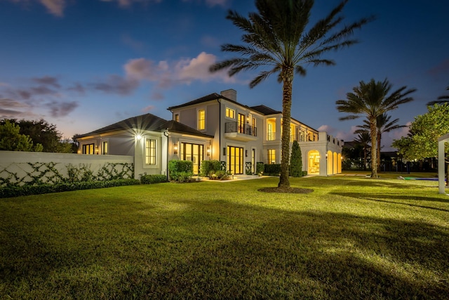 back house at dusk with a yard and french doors