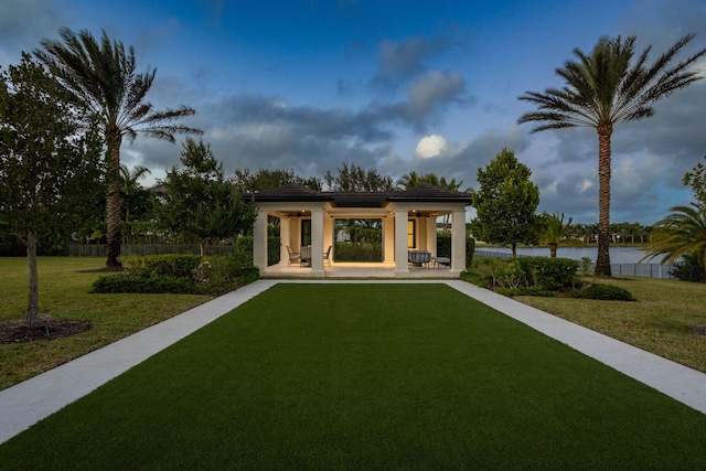 rear view of house featuring a water view and a lawn