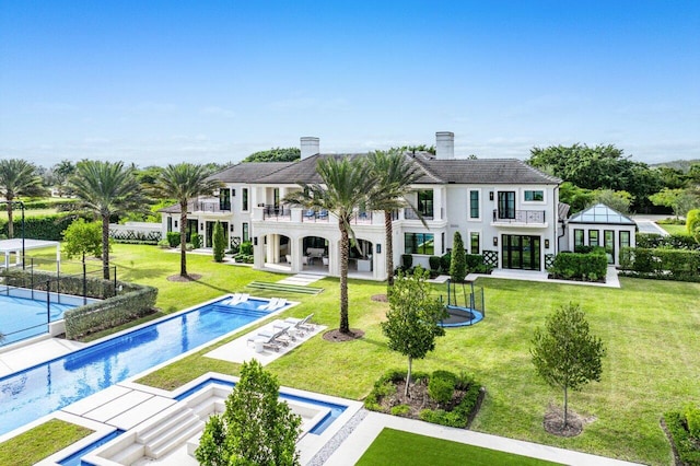 rear view of property featuring a yard, a patio area, and a balcony