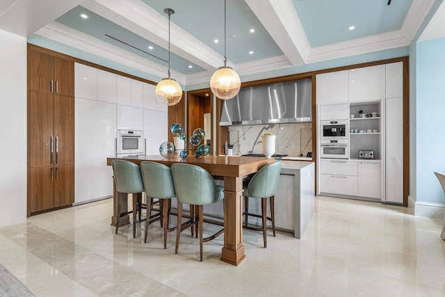 kitchen featuring pendant lighting, a kitchen island with sink, wall chimney exhaust hood, and white cabinets