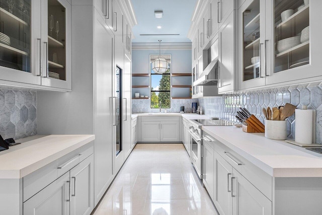 kitchen featuring crown molding, stainless steel stove, white cabinets, decorative light fixtures, and wall chimney exhaust hood