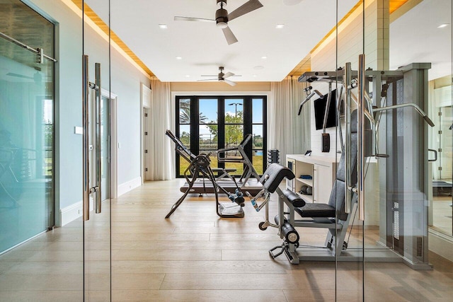 exercise room with ceiling fan and light hardwood / wood-style flooring