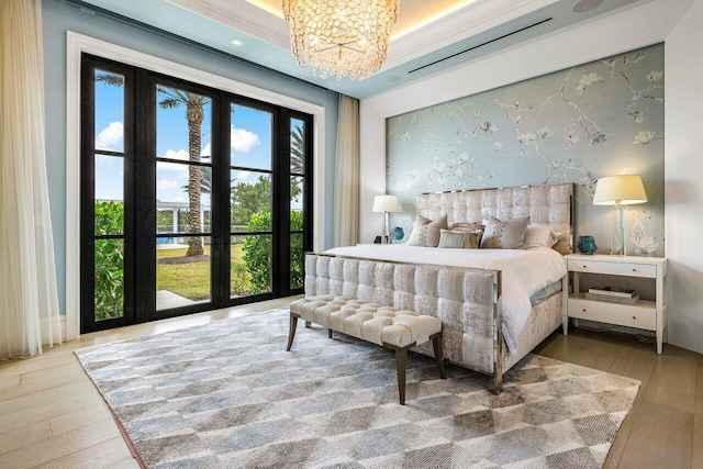 bedroom with an inviting chandelier, light hardwood / wood-style floors, and french doors