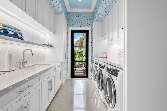 clothes washing area featuring cabinets, ornamental molding, sink, and independent washer and dryer