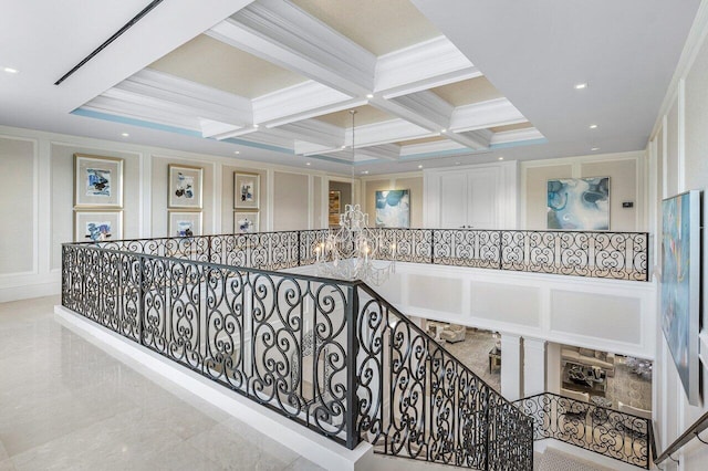 hall featuring beamed ceiling, ornamental molding, coffered ceiling, and a chandelier