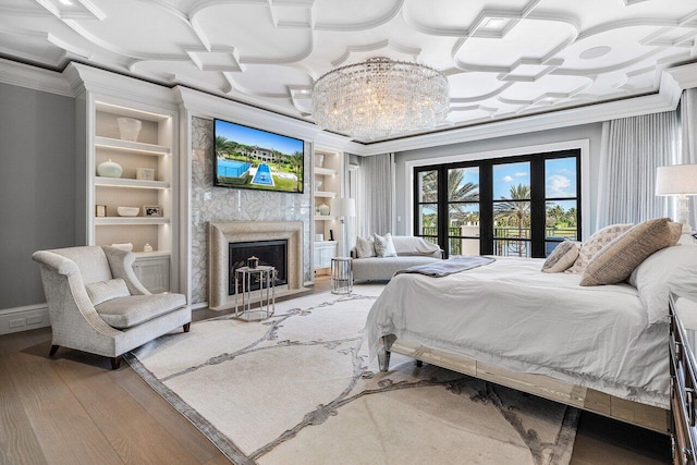 bedroom with crown molding, hardwood / wood-style floors, a fireplace, and french doors