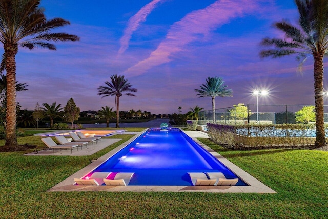 pool at dusk featuring a yard