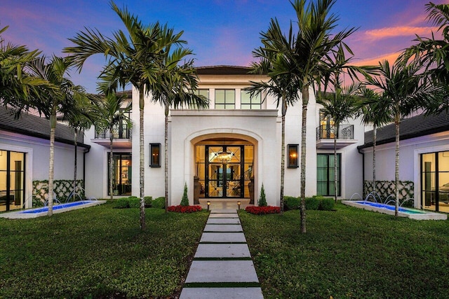 exterior entry at dusk featuring a lawn