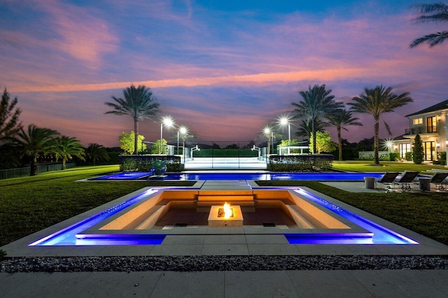 pool at dusk featuring a yard