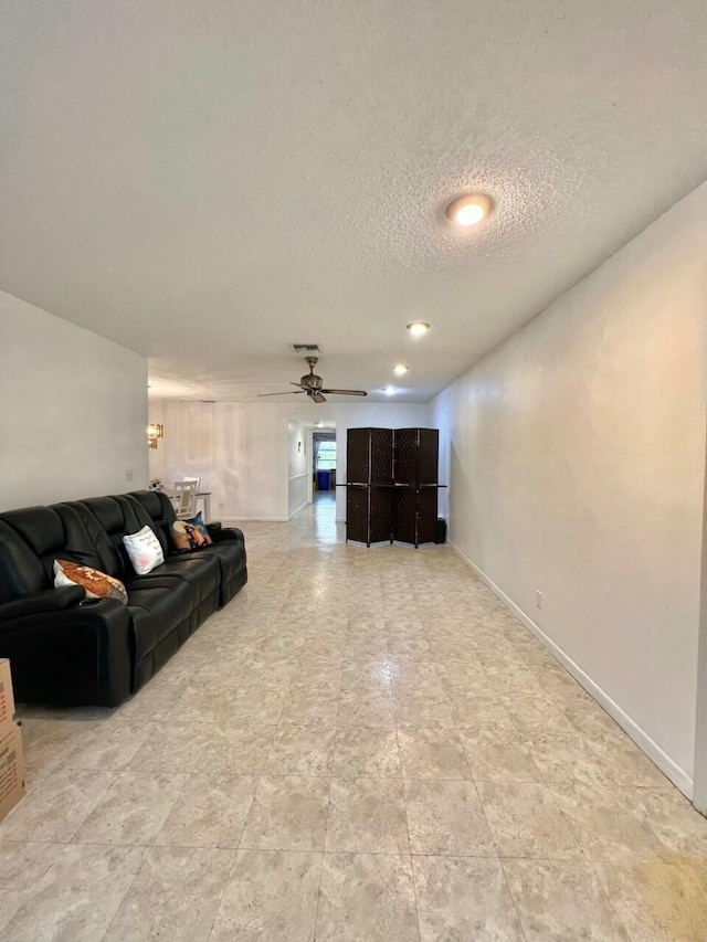 living room featuring ceiling fan and a textured ceiling