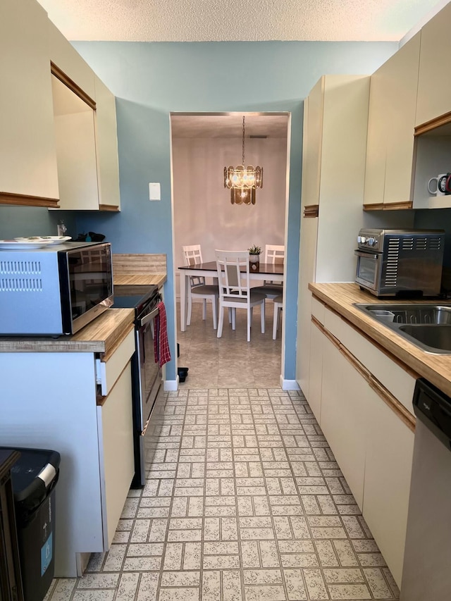 kitchen with wood counters, cream cabinets, an inviting chandelier, decorative light fixtures, and stainless steel appliances